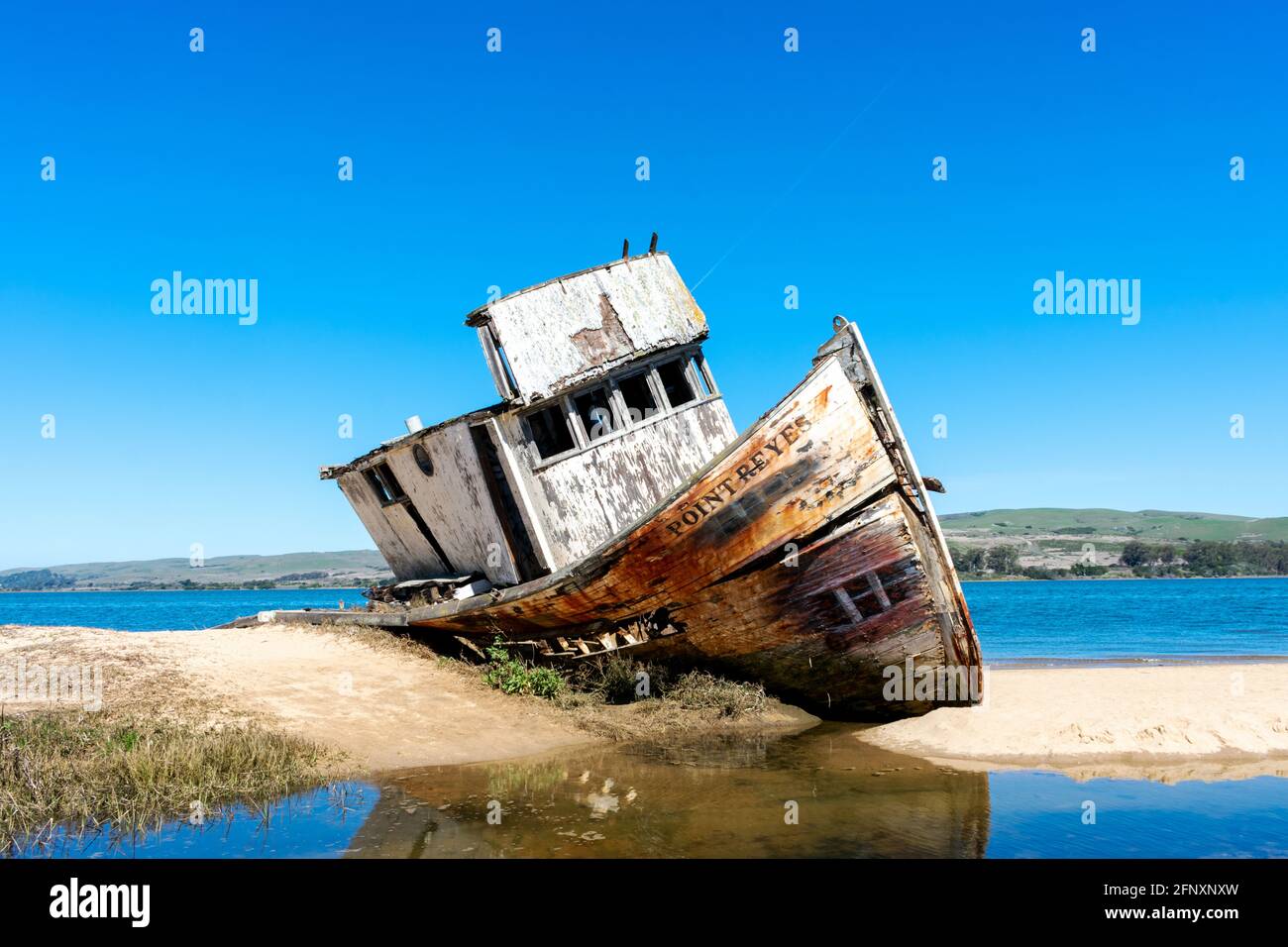 Punto Reyes naufragio, una barca abbandonata su una barra di sabbia al largo della costa di Tomales Bay in California sotto il cielo blu - Inverness, California, USA - 202 Foto Stock