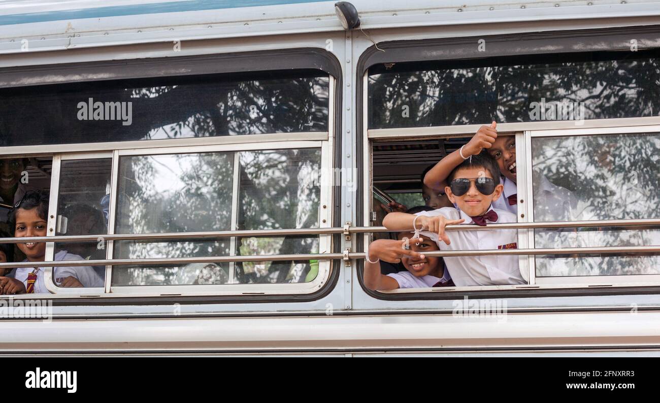 Gli studenti dello Sri Lanka si sono gesticulanti, dando segni di pace fuori dalla finestra degli autobus, Anuradhapura, Sri Lanka Foto Stock