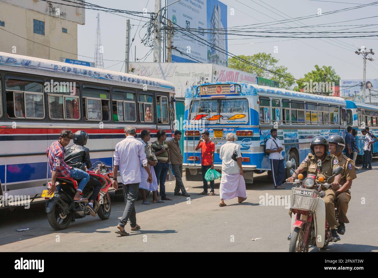 I pedoni che camminano intorno al bus-stand di Jaffna mentre la polizia nelle uniformi di kaki guidano oltre sulla moto, Sri Lanka Foto Stock