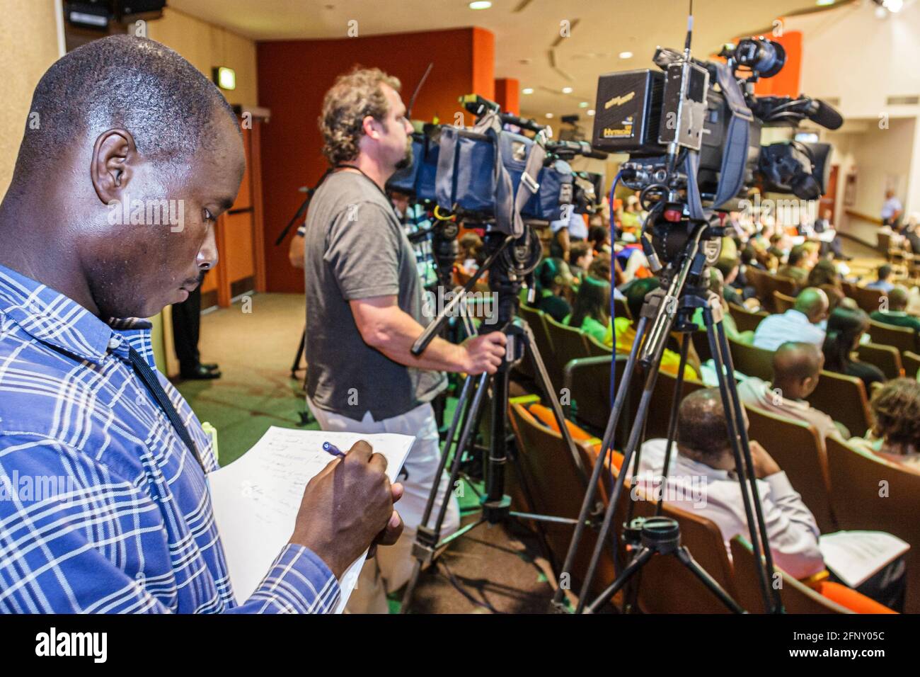 Miami Florida,riunione del Consiglio di Educazione,discutere di chiusura della scuola membri,uomo nero giornalista maschio reporter media,telecamere televisive, Foto Stock