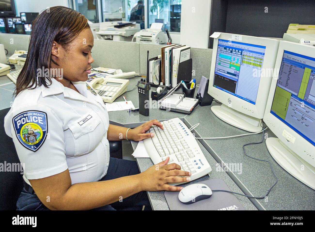 North Miami Beach, Florida, Dipartimento di polizia, donna afroamericana, agente di polizia, dispatcher per lo schermo del computer, scrivania per i dipendenti, forze dell'ordine Foto Stock
