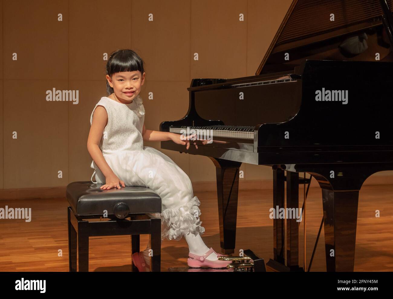 Ragazza asiatica con pianoforte a coda in concerto. Foto Stock