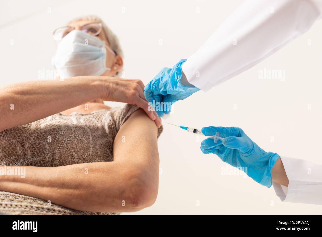 Un medico che dà un'iniezione di un vaccino covid-19 ad un paziente anziano. Concetto di vaccinazione. Foto Stock