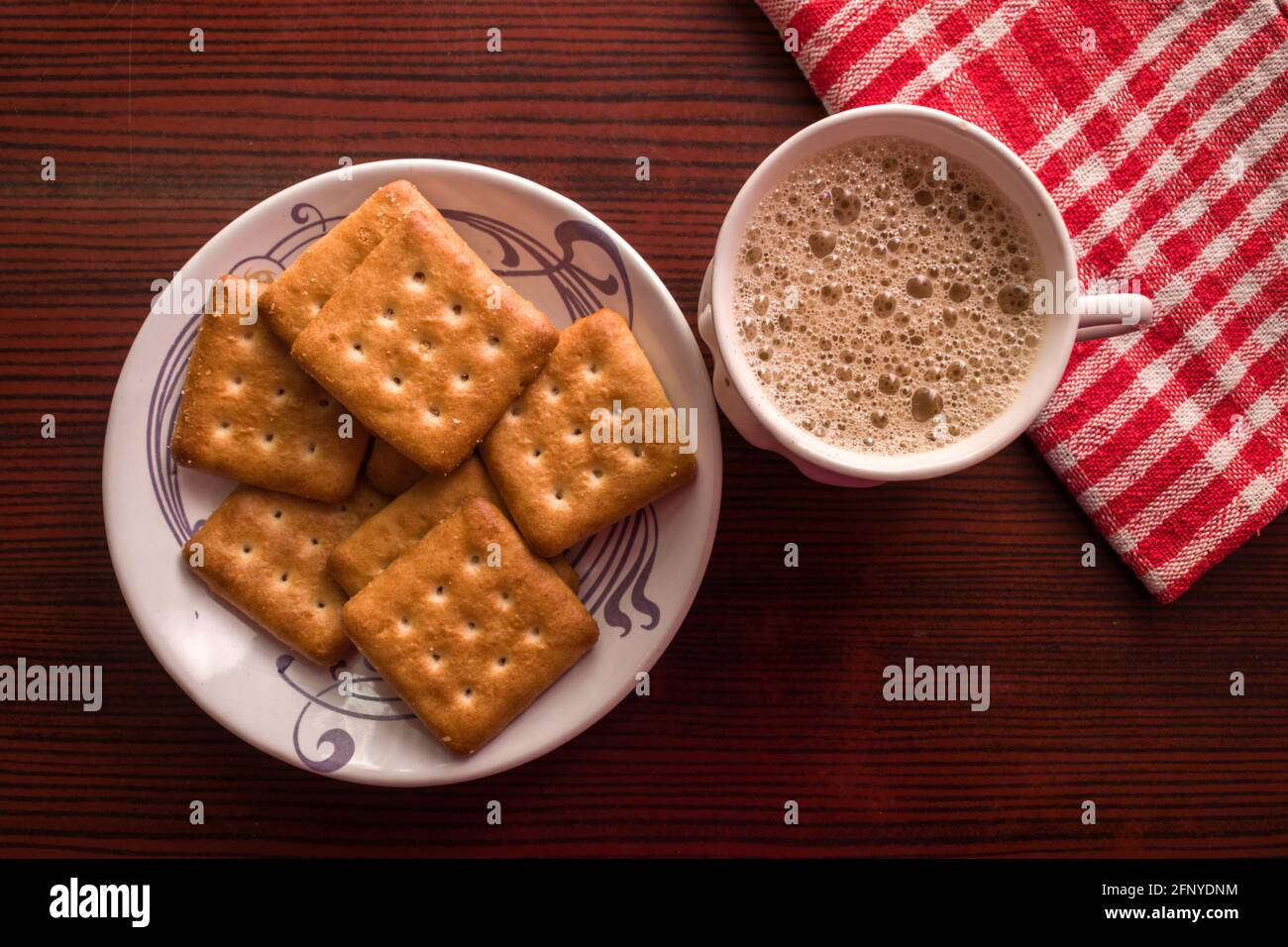 Vista dall'alto di una tazza di tè caldo masala chai con alcuni biscotti su sfondo di legno Foto Stock