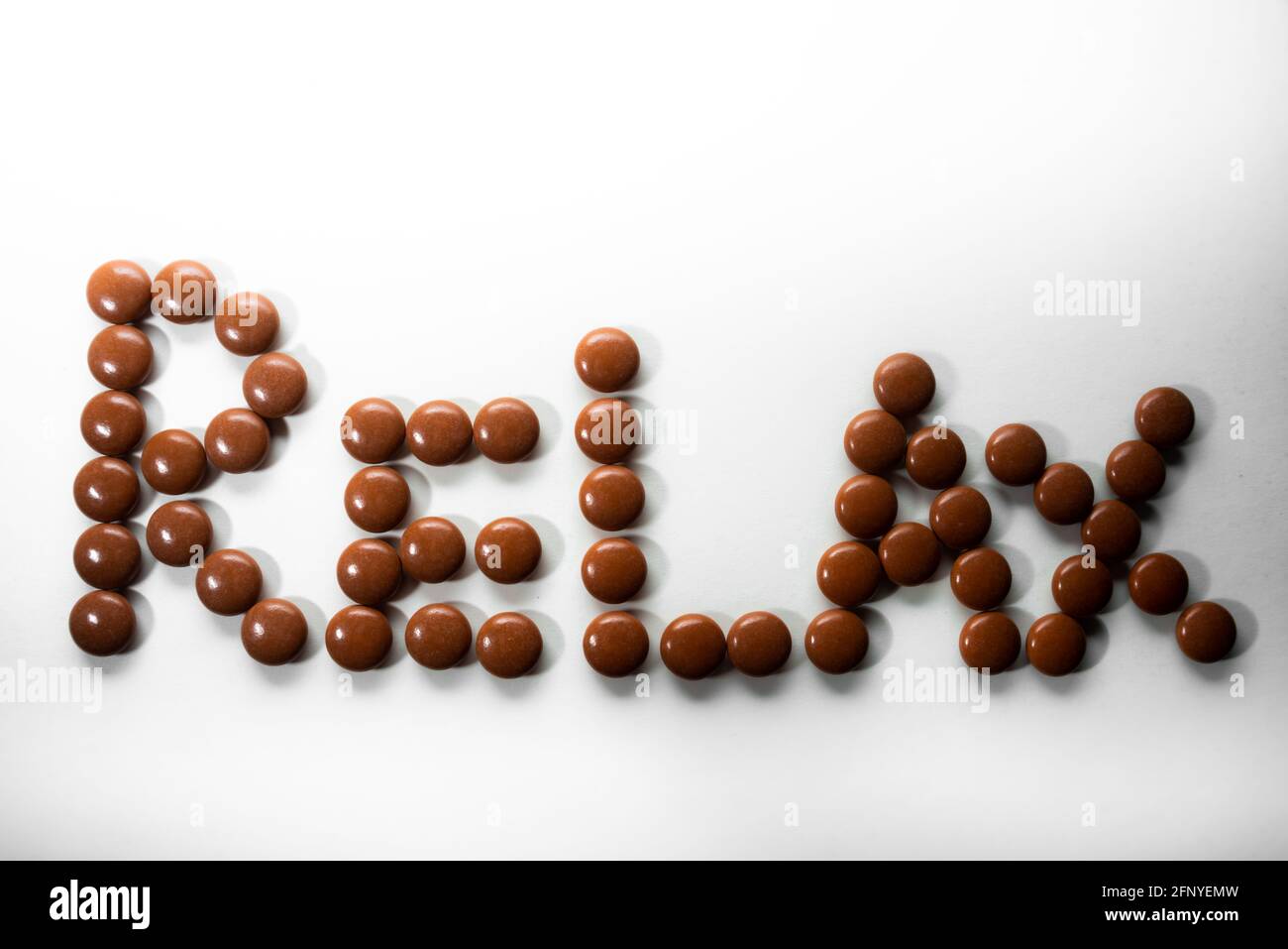 Naturale Anti stress o dormire compresse per aiutare il relax ortografia fuori la parola relax su sfondo bianco, medicina alternativa a base di erbe. Foto Stock