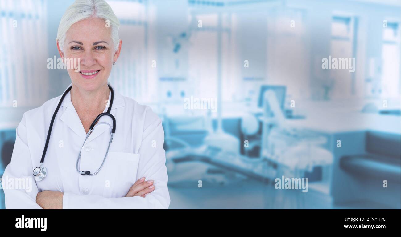 Ritratto di caucasica anziana dottoressa sorridente contro ospedale in sfondo Foto Stock