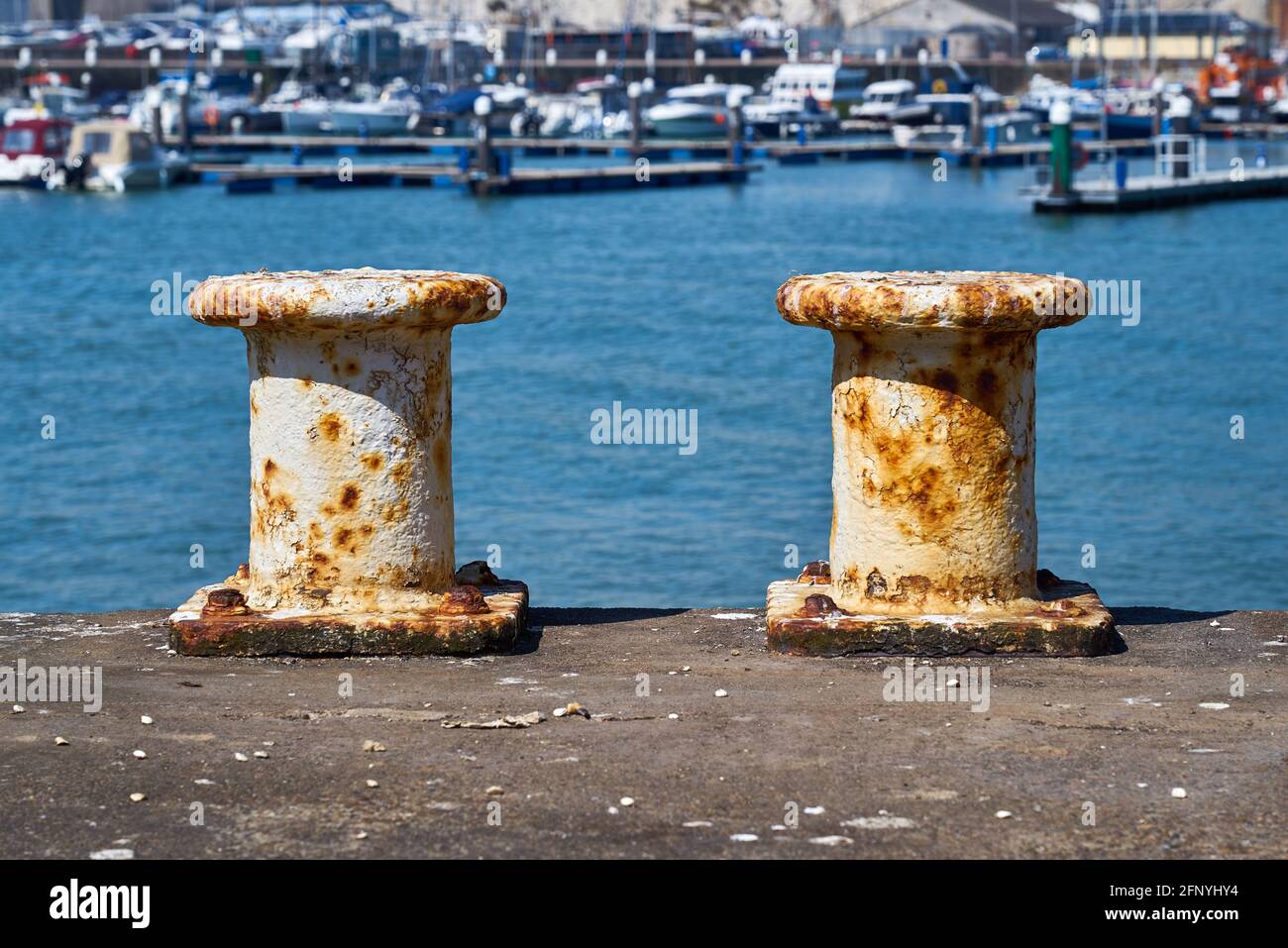 Due pilastri per ormeggio barche con il porto in lo sfondo Foto Stock