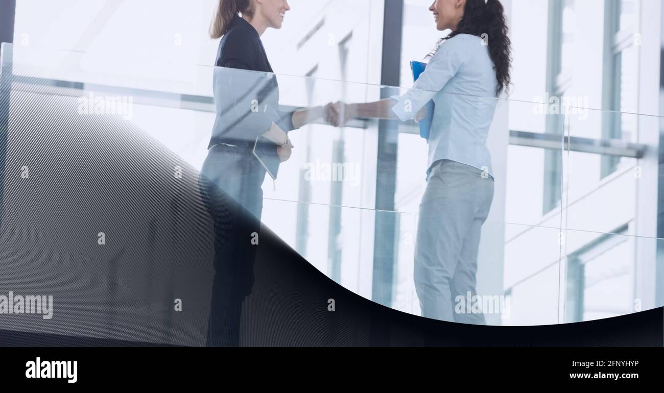 Sezione centrale di due uomini d'affari che scuotono le mani in ufficio contro background tecnologico Foto Stock