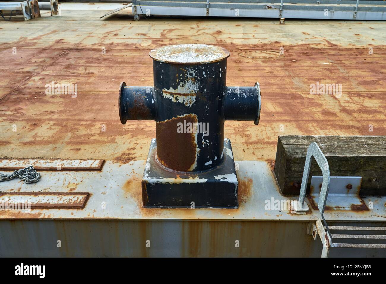 Un bollard di ormeggio cruciforme che mostra segni di usura della corda e catene Foto Stock