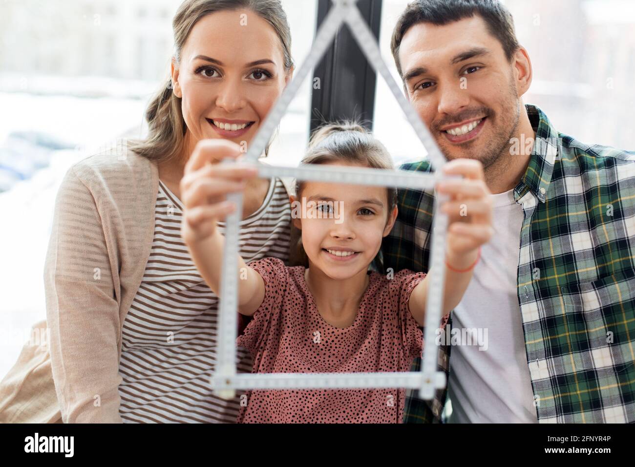 felice famiglia con il righello pieghevole che si sposta in nuova casa Foto Stock