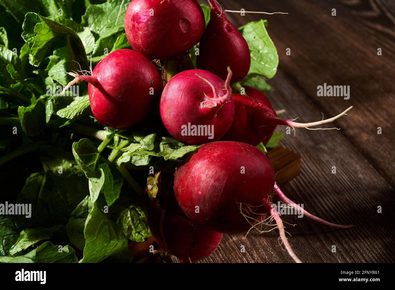 Rafano rosso fresco intero su tavola di legno. Foto Stock