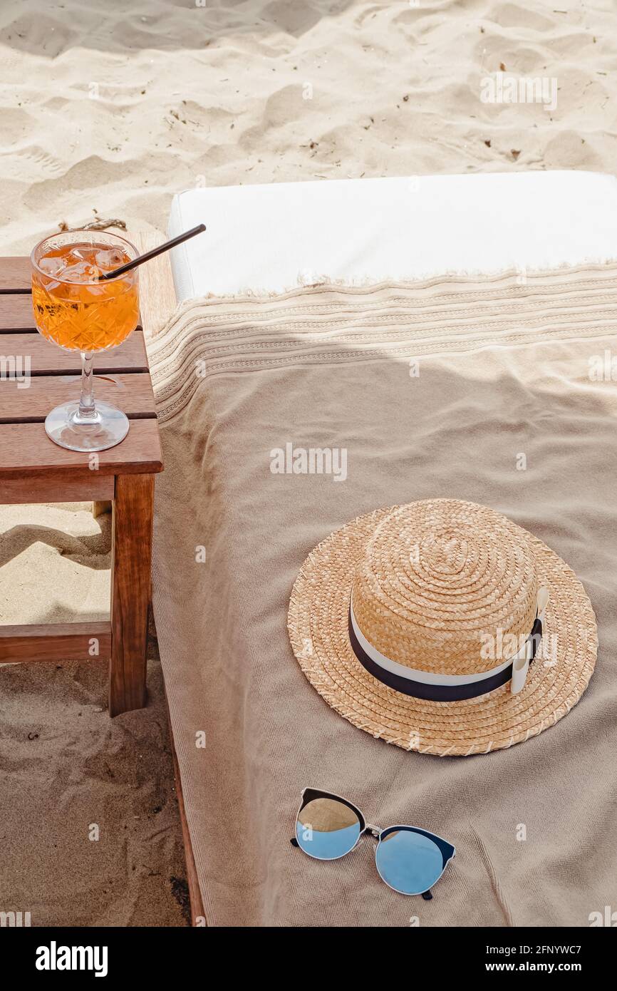 Un bicchiere di aperol Spritz , cappello di paglia e occhiali da sole sulla spiaggia Foto Stock