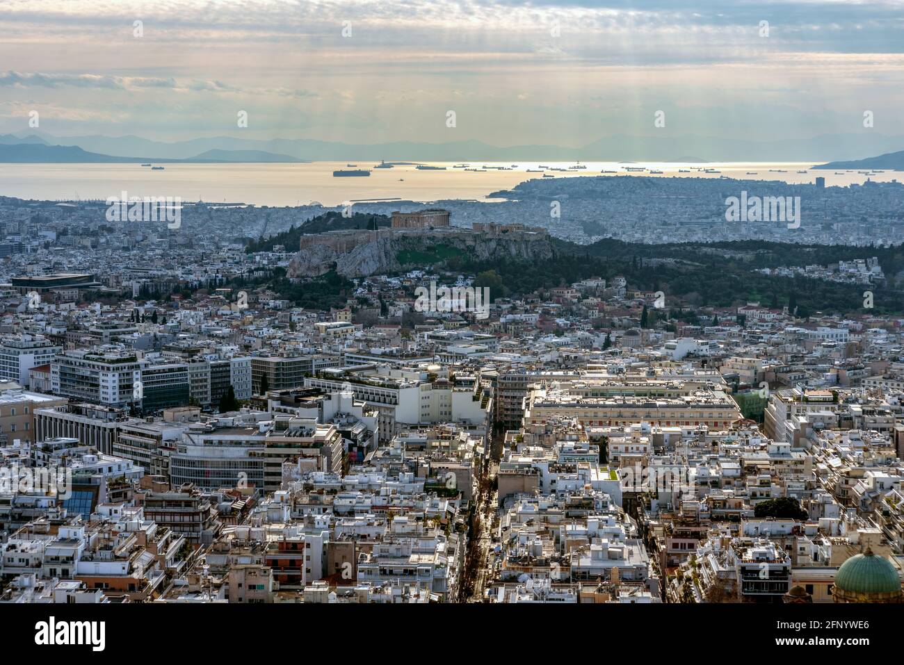 Vista panoramica del bacino dell'Attica al tramonto visto dalla collina di Lycabettus. Acropoli con tempio del Partenone, navi ormeggiate al porto del Pireo, raggi del sole Foto Stock