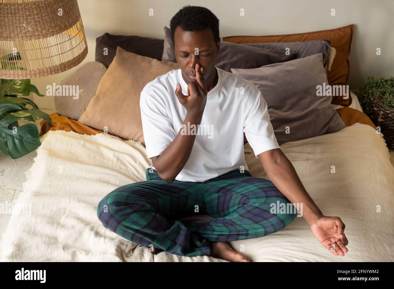 Giovane uomo africano che pratica la lezione di yoga, facendo Nostril alternativo respirazione esercizio Foto Stock