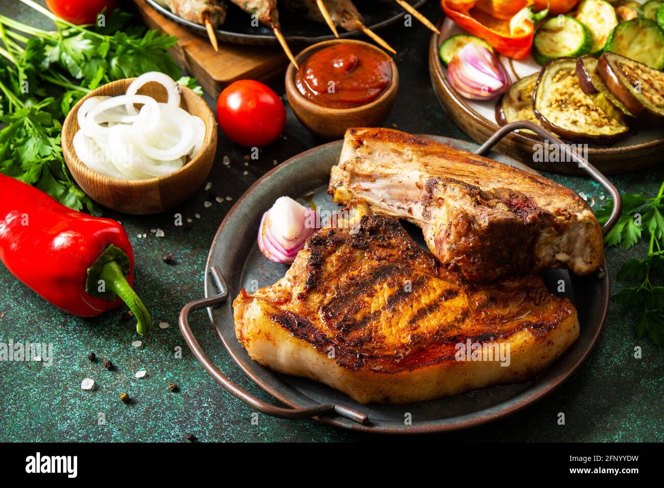 Kebab Kofta fatti in casa, bistecca alla griglia e verdure alla griglia su uno spiedino con verdure e salsa di pomodoro su un piano di pietra scuro. Foto Stock