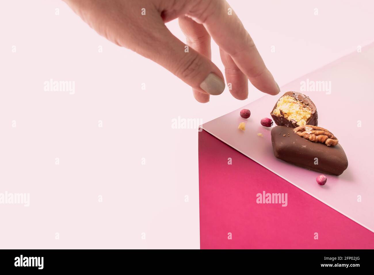 Mano della donna con cioccolato fondente fatto a mano con frutti di bosco e noci Foto Stock