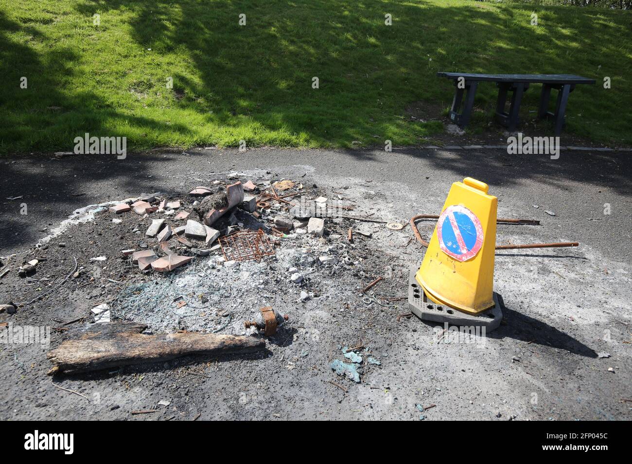 Bidone di rifiuti distrutto da un incendio impostato da vandali con traffico cono che avverte le persone del pericolo Foto Stock