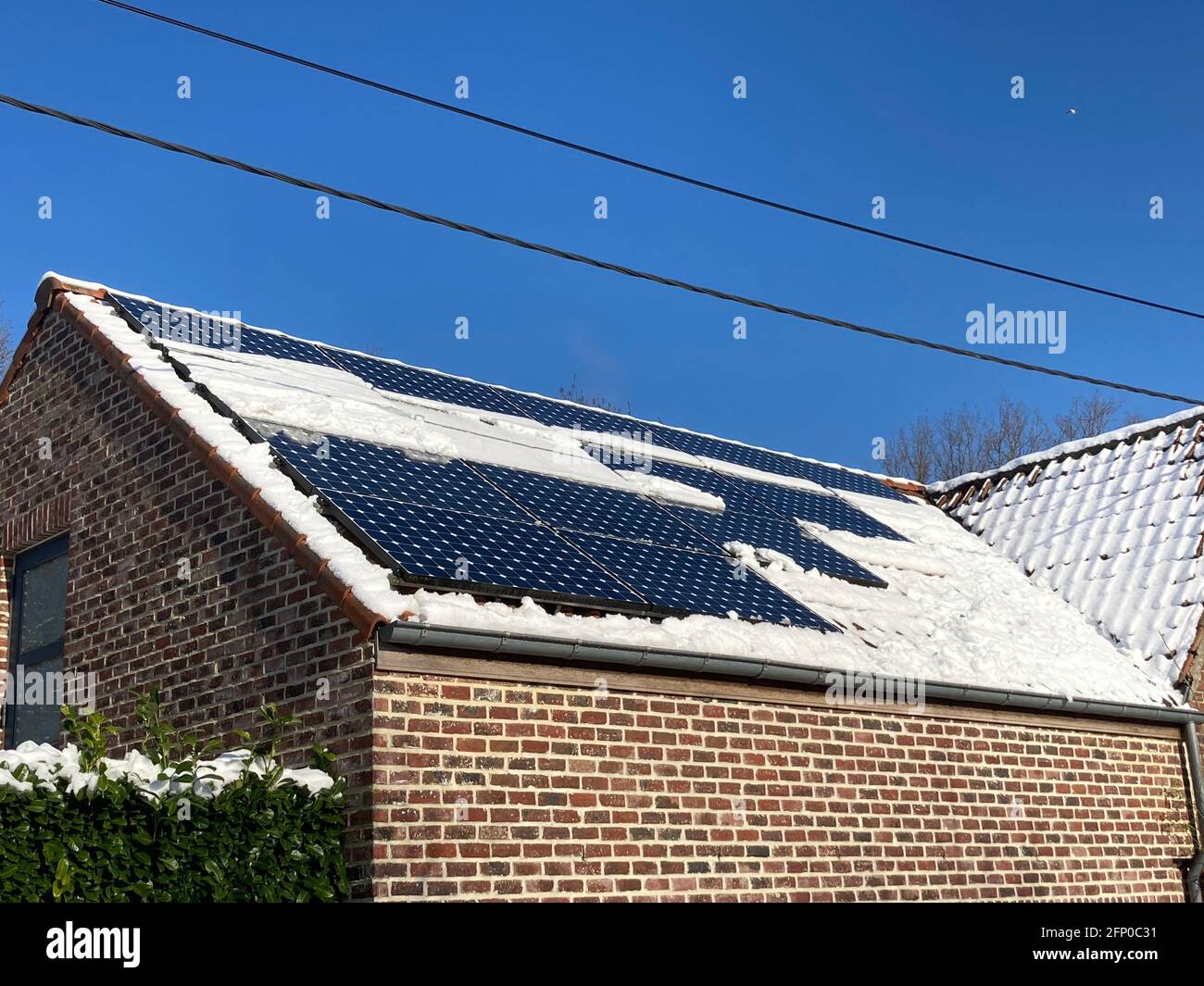 neve che ricopre parzialmente i pannelli solari su un tetto Foto Stock