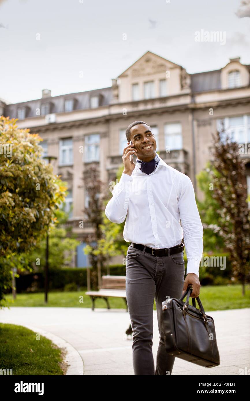 Bel giovane uomo d'affari afro-americano che usa un cellulare su una strada Foto Stock