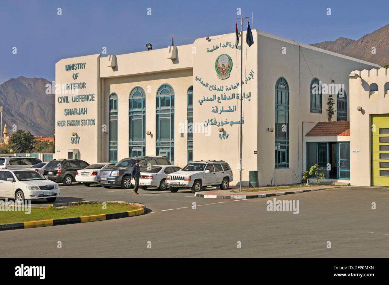 Insegne bilingue esterno dell'edificio governativo del Ministero degli interni Emirato della Difesa civile di Sharjah e parcheggio degli Emirati Arabi Uniti Medio Oriente Foto Stock