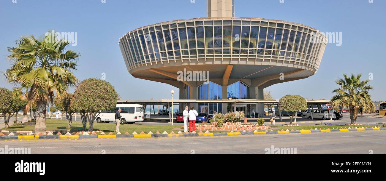 Turisti fuori ristorante alla base di alta torre di osservazione in Zona dei servizi a metà strada sulla King Fahd Causeway autostrada che collega Bahrain In Arabia Saudita Foto Stock