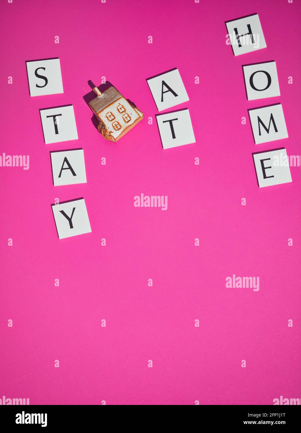 Direttamente sopra di casa modello e le parole di messaggio rimangono a casa su sfondo rosa. Concetto di sicurezza, consulenza, prevenzione Foto Stock