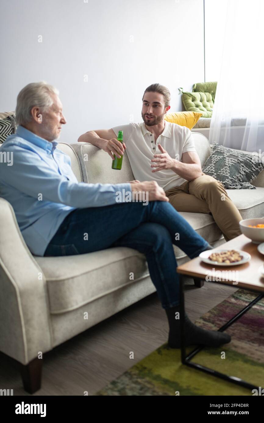 Anziani e giovani che chiacchierano sul divano Foto Stock