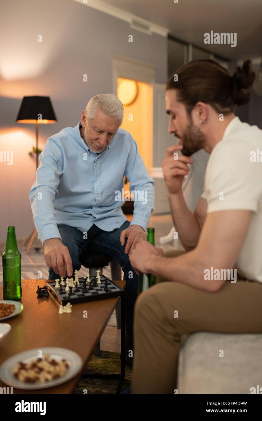 Nonno e nipote che pensano durante il gioco degli scacchi Foto Stock