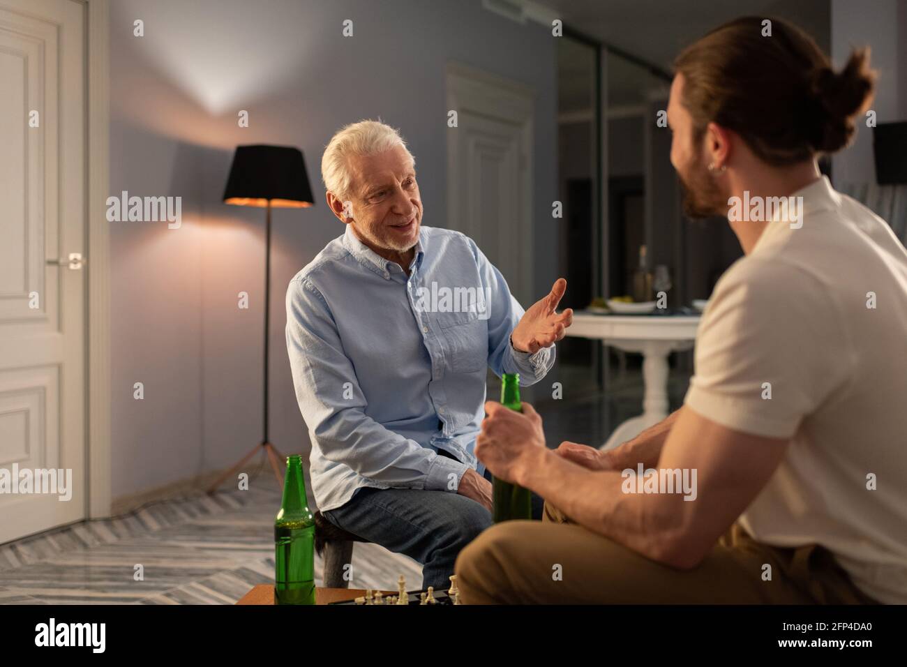 Uomini giovani e anziani che parlano dopo il gioco degli scacchi Foto Stock