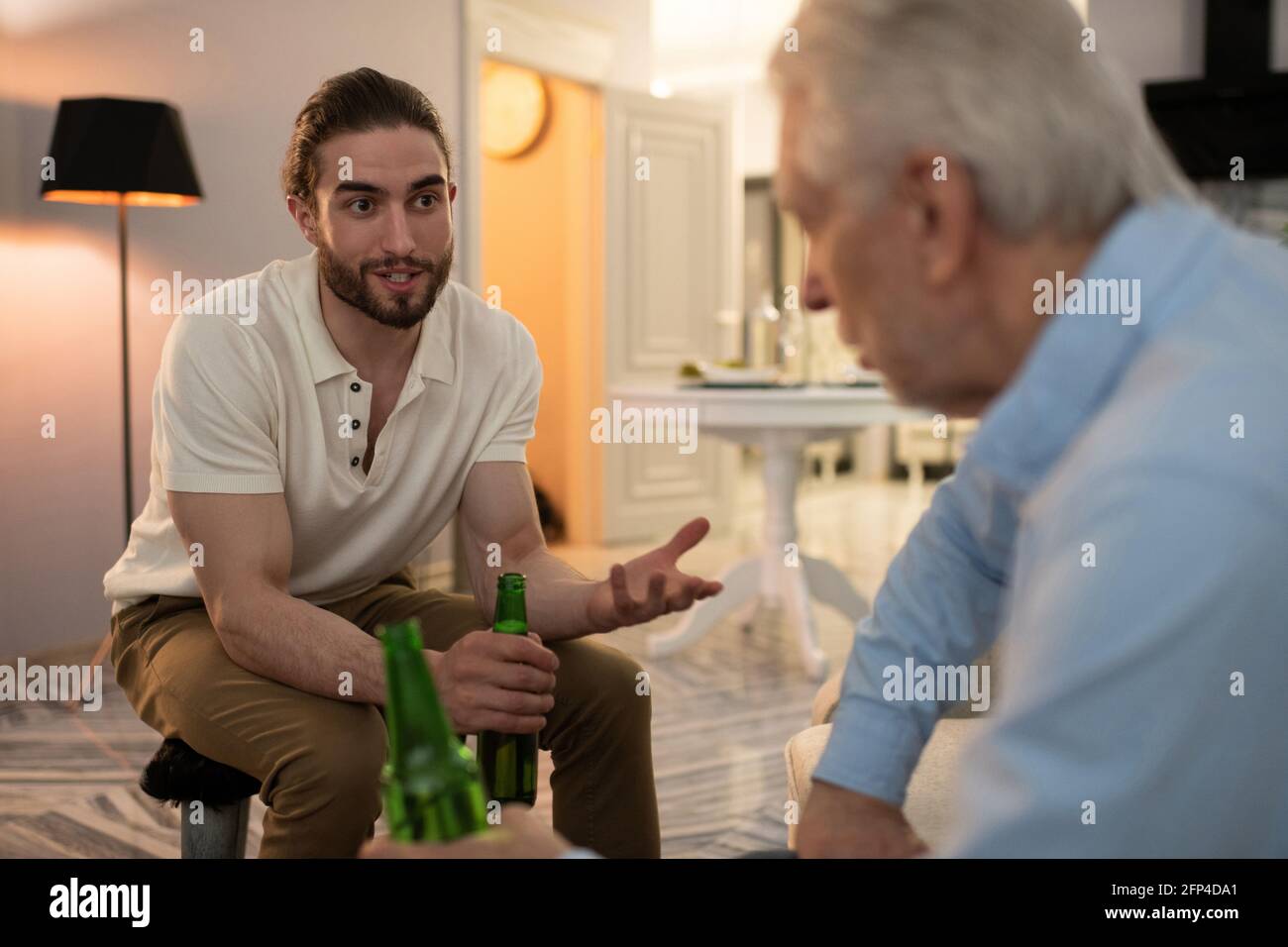 Giovane che beve birra e parla con nonno Foto Stock