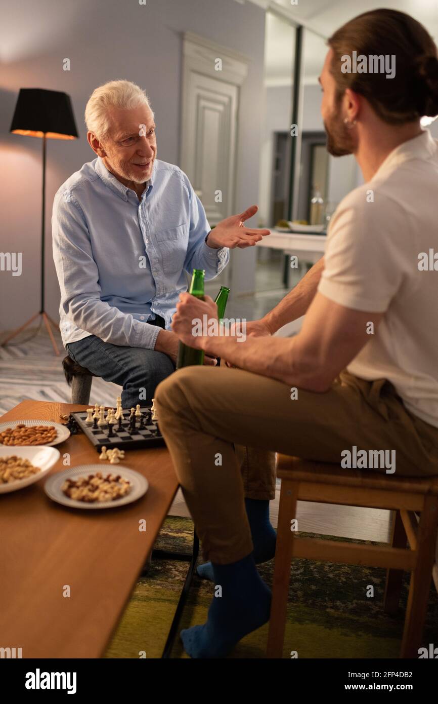 Uomo anziano che discute il gioco degli scacchi con il nipote Foto Stock