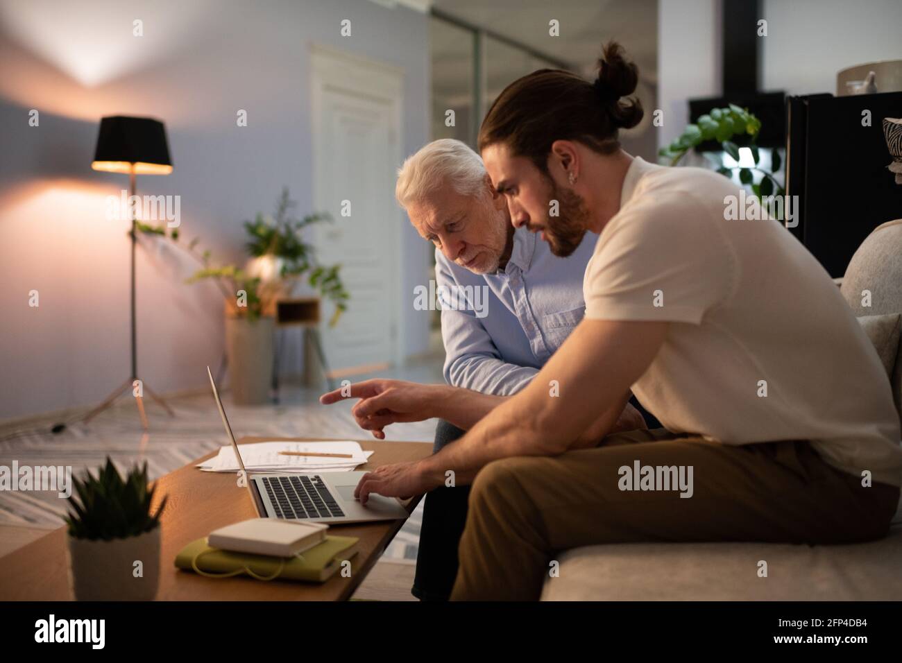 Nipote che insegna al nonno di usare il laptop Foto Stock