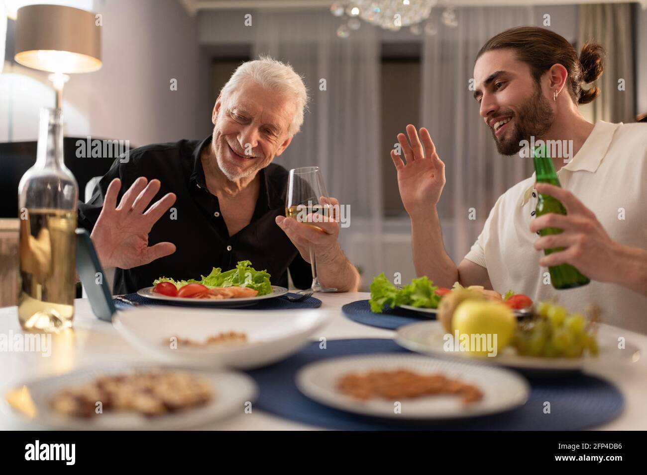 Giovani e anziani che fanno videochiamata e che cenano Foto Stock