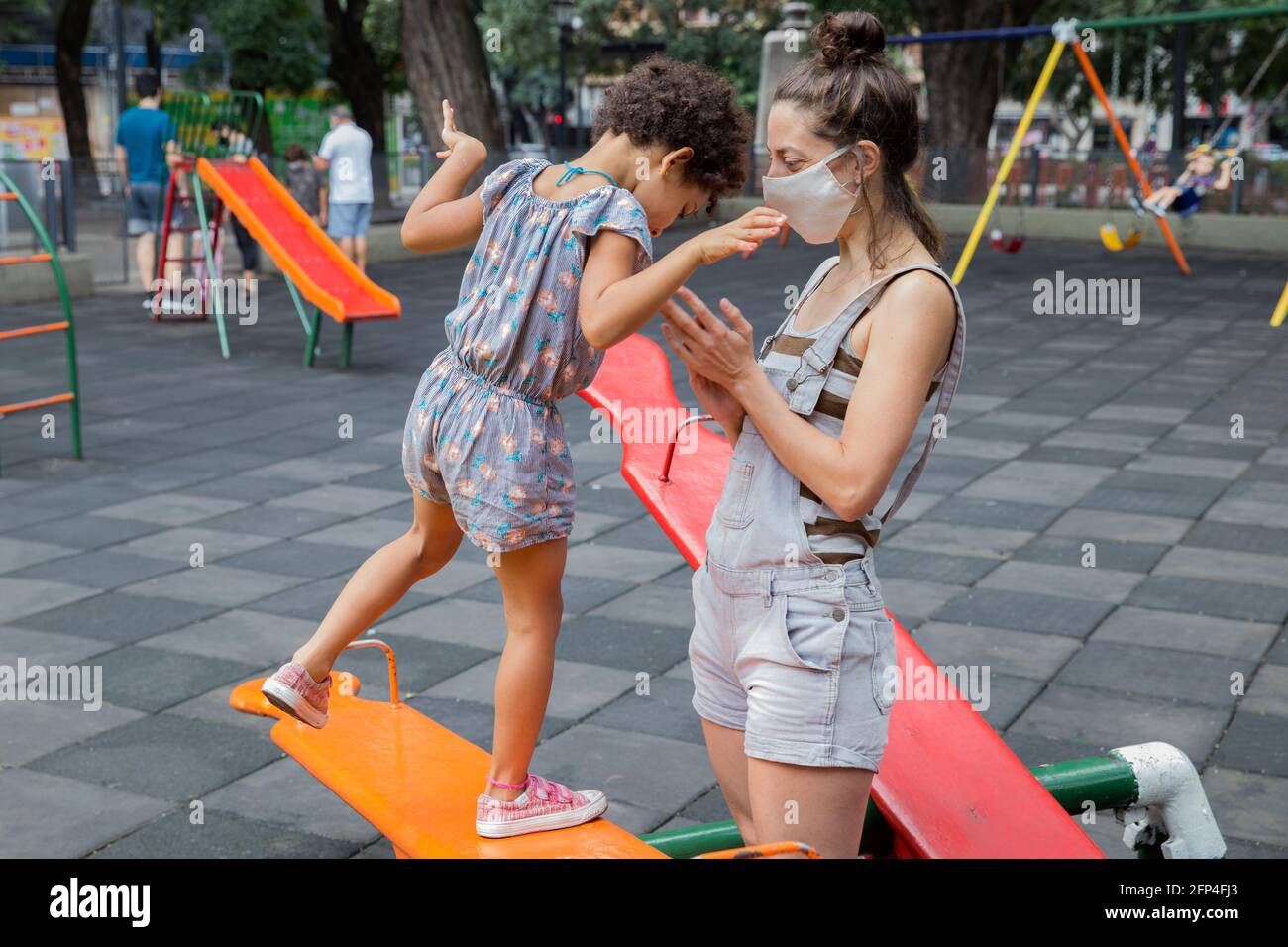 Mamma e figlia si divertiranno al parco giochi all'aperto in una nuova vita normale. Foto Stock