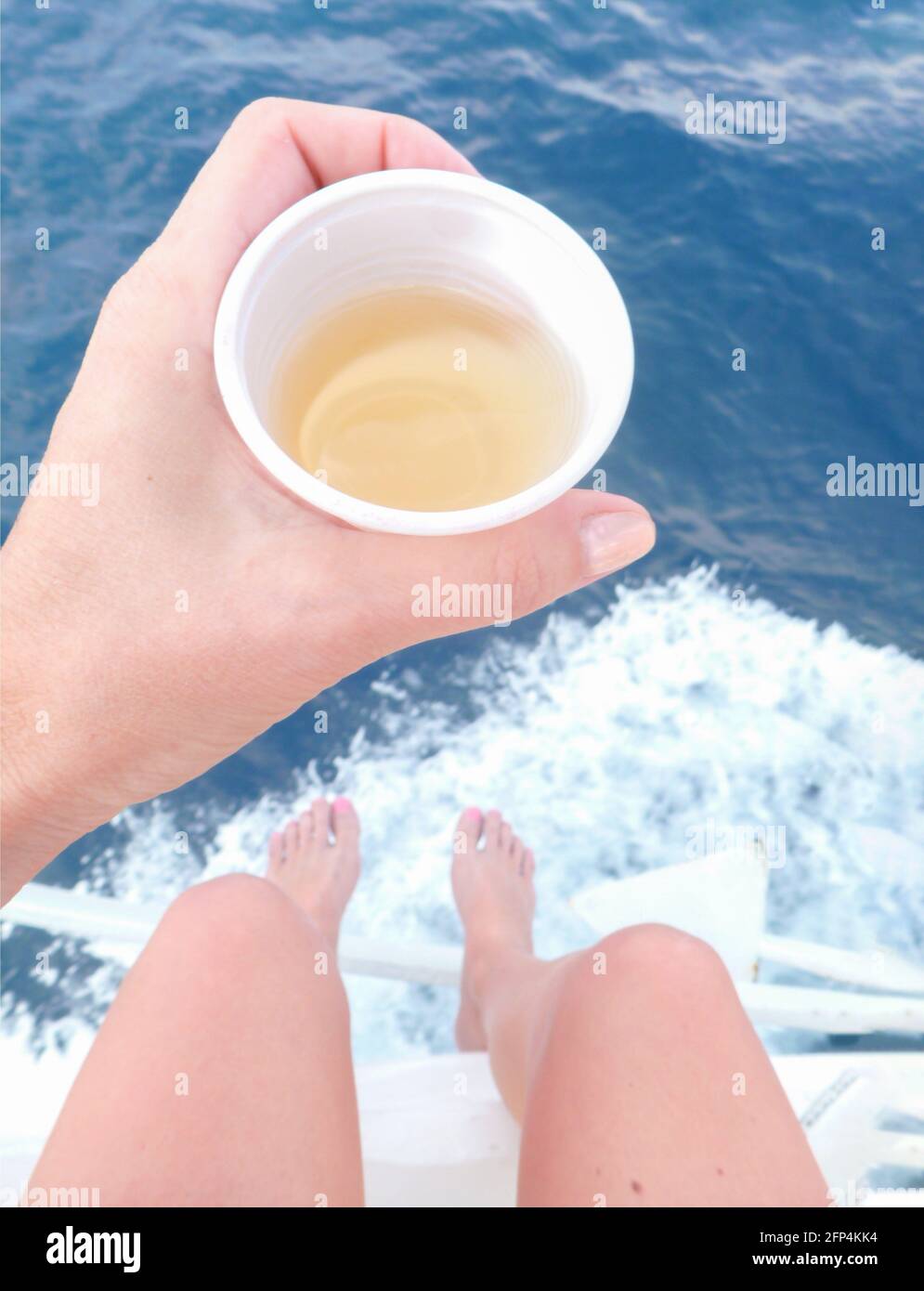 Mano della donna che tiene un bicchiere di vino sul mare Foto Stock