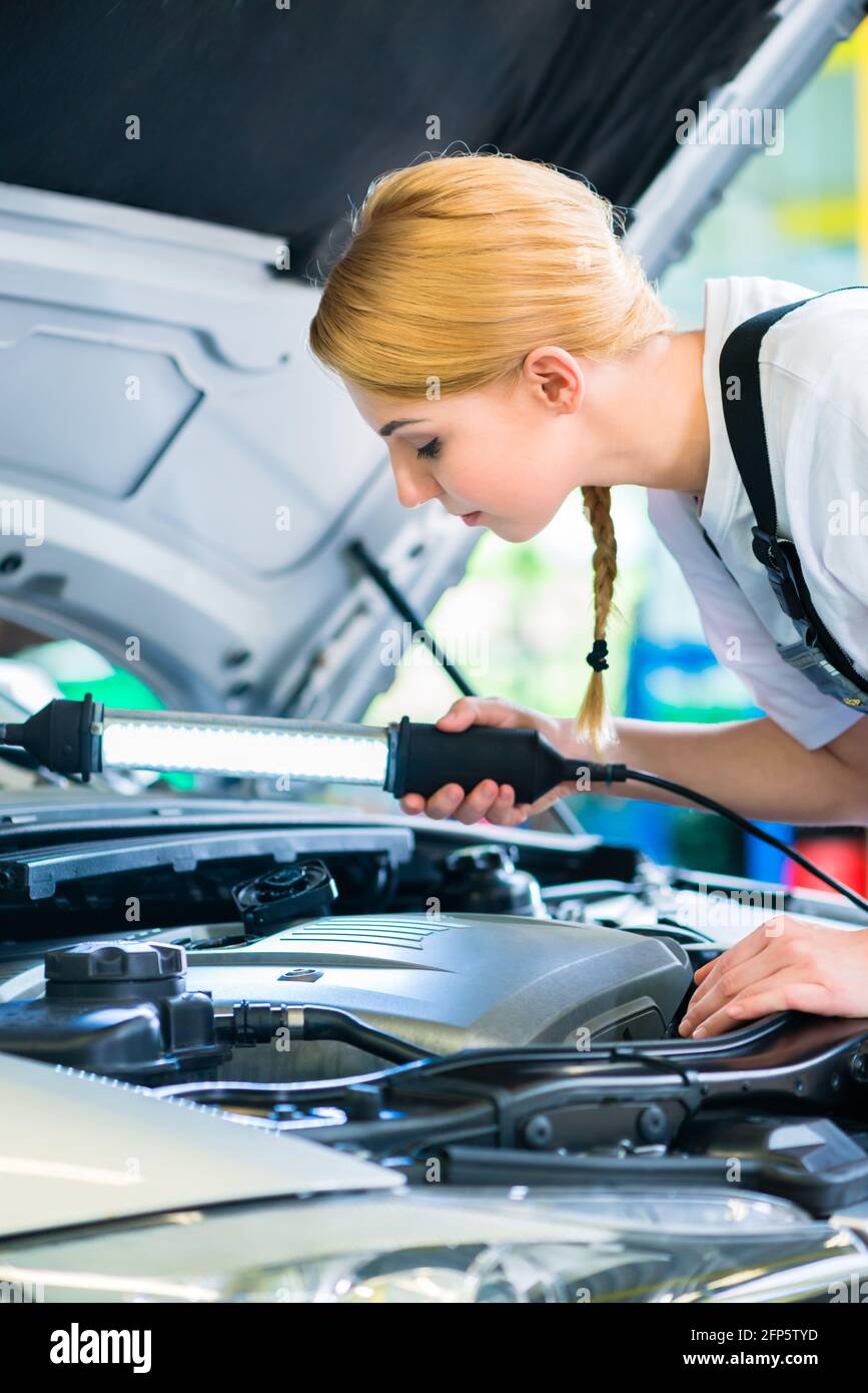 Femmina esaminare meccanico auto a motore con luce in officina Foto Stock