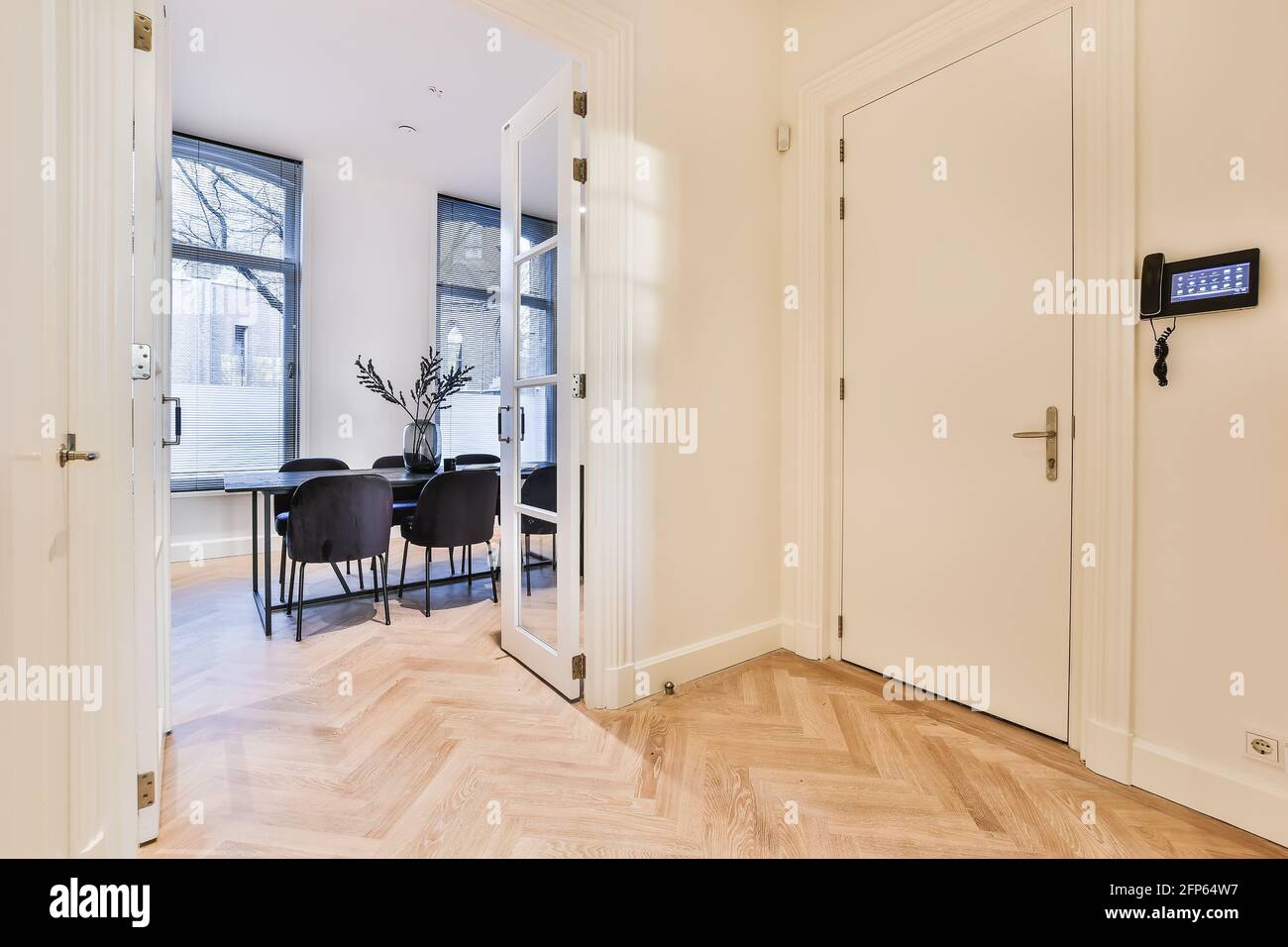 Corridoio con sistema di sicurezza a parete e parquet in legno pavimento con porta aperta al soggiorno Foto Stock