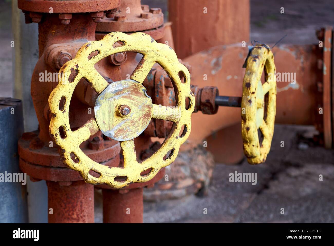 Due valvole industriali marrone retro design con volantini gialli su cemento fondo industriale di impianto chimico con copyspace. Concetto di valvola Foto Stock