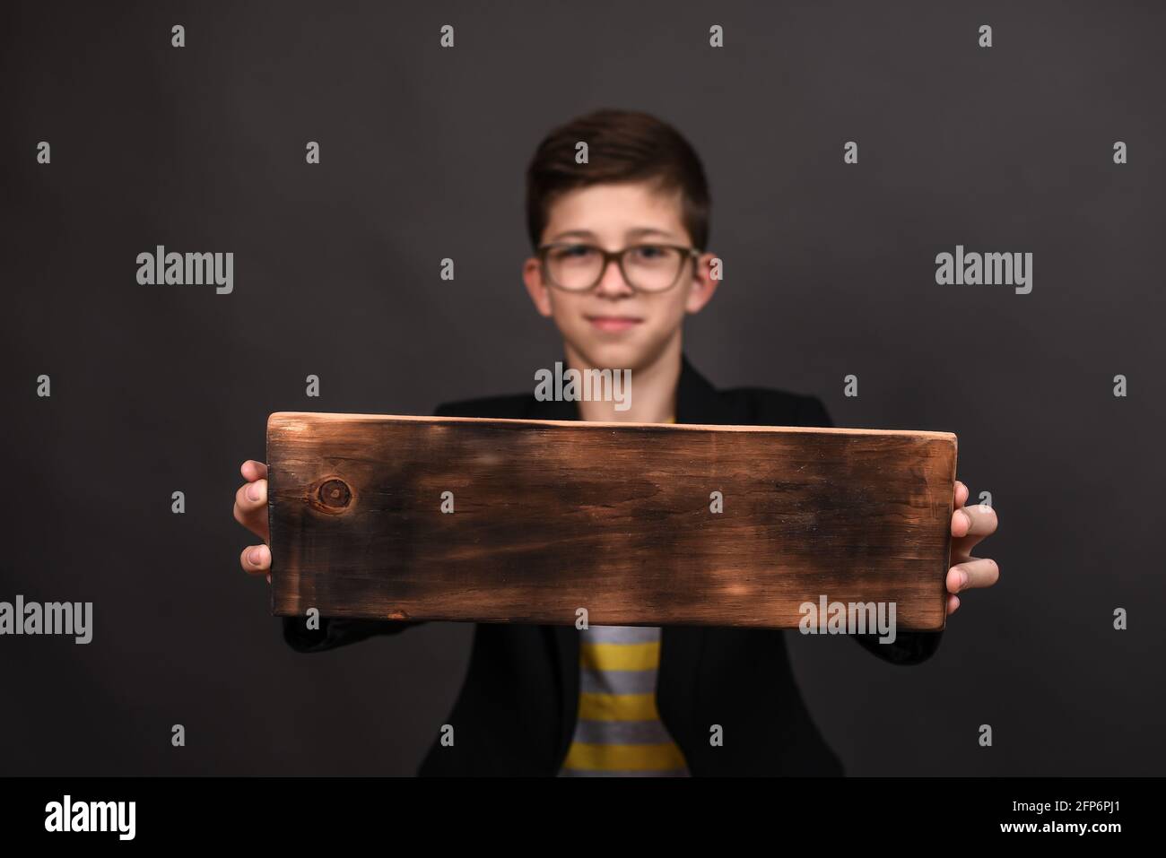 un bel ragazzo tiene un cartello di legno con uno spazio per la copia e un posto per l'iscrizione. Sfocatura selettiva Foto Stock