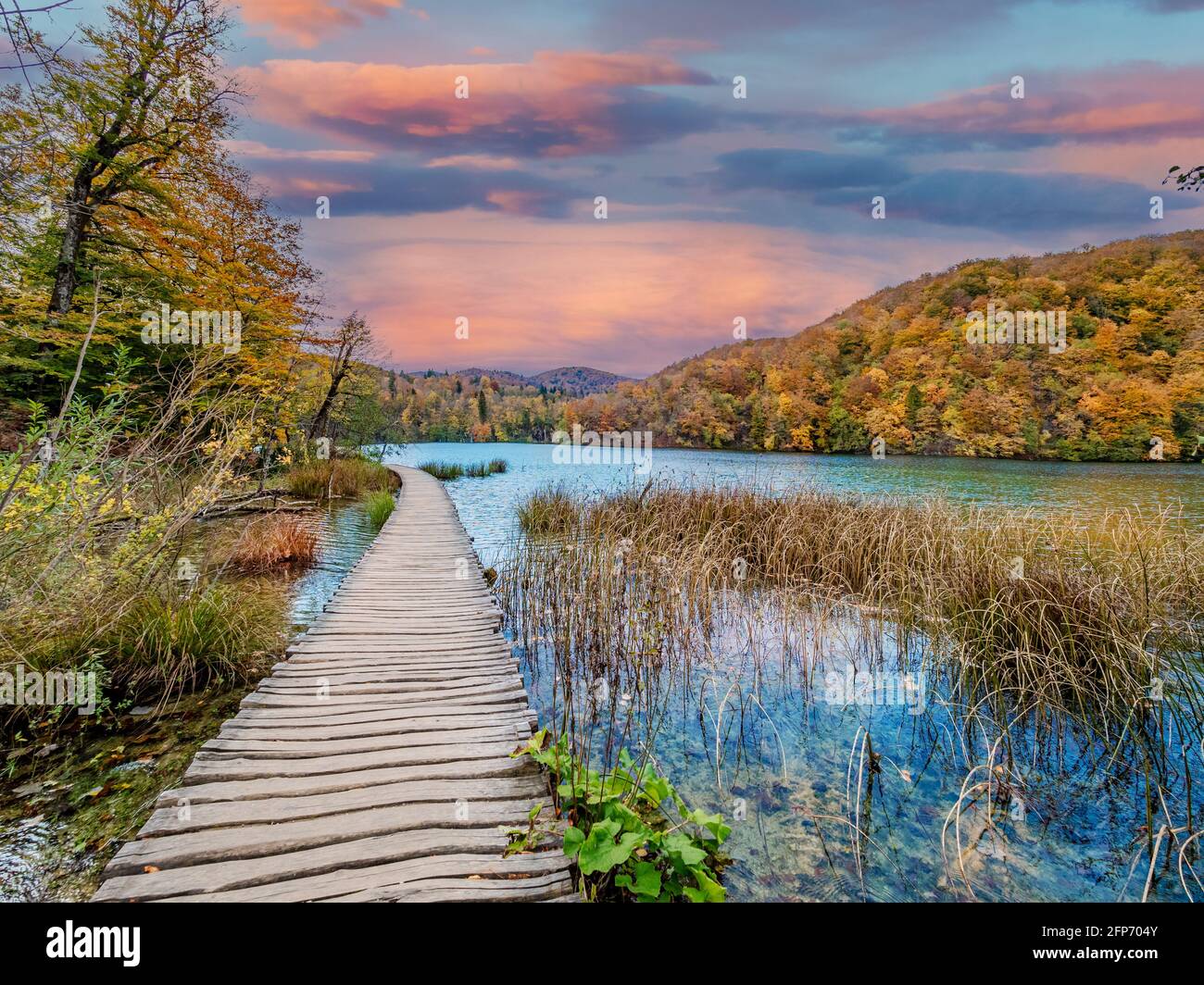Splendido paesaggio autunnale con nuvole colorate riflesse nel lago smeraldo al tramonto a Plitvice, Croazia Foto Stock