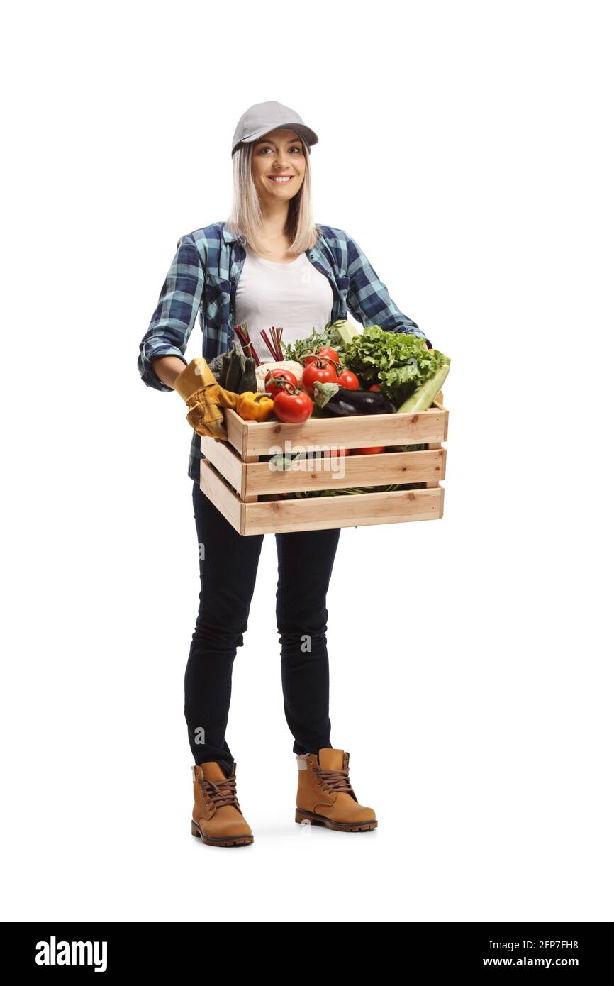 Ritratto a lunghezza intera di una giovane donna contadina che porta un cassa con verdure e sorridente isolato su sfondo bianco Foto Stock