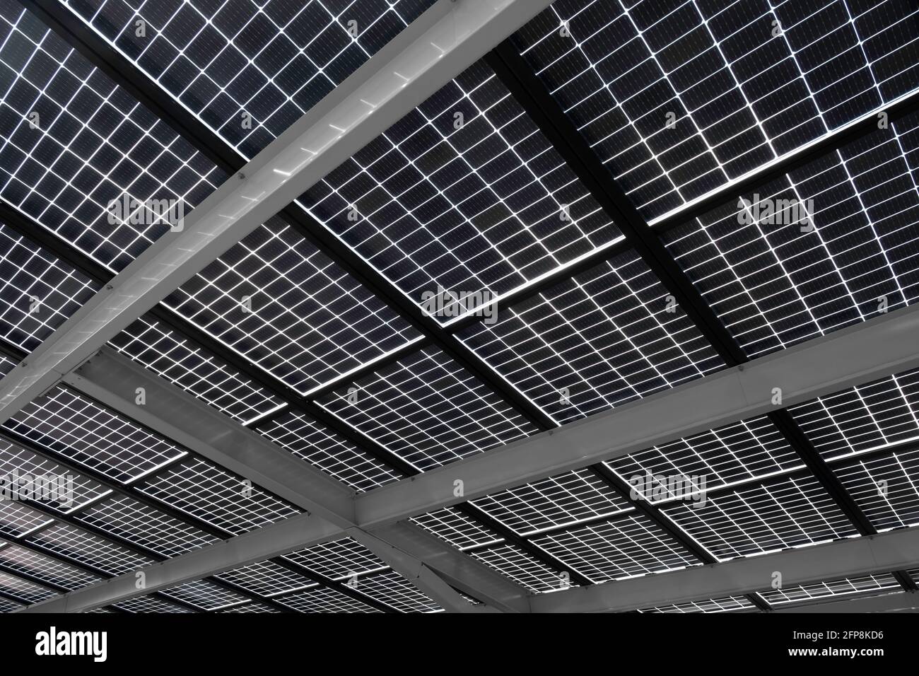 Pannelli solari installati su travi in acciaio per coprire un parcheggio, visto dal basso. Energia sostenibile e ombra allo stesso tempo Foto Stock
