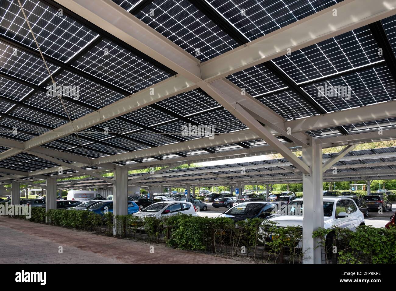 Pannelli solari installati sulla tettoia di un parcheggio auto nel centro della città olandese Dronten. Energia sostenibile e ombra Foto Stock