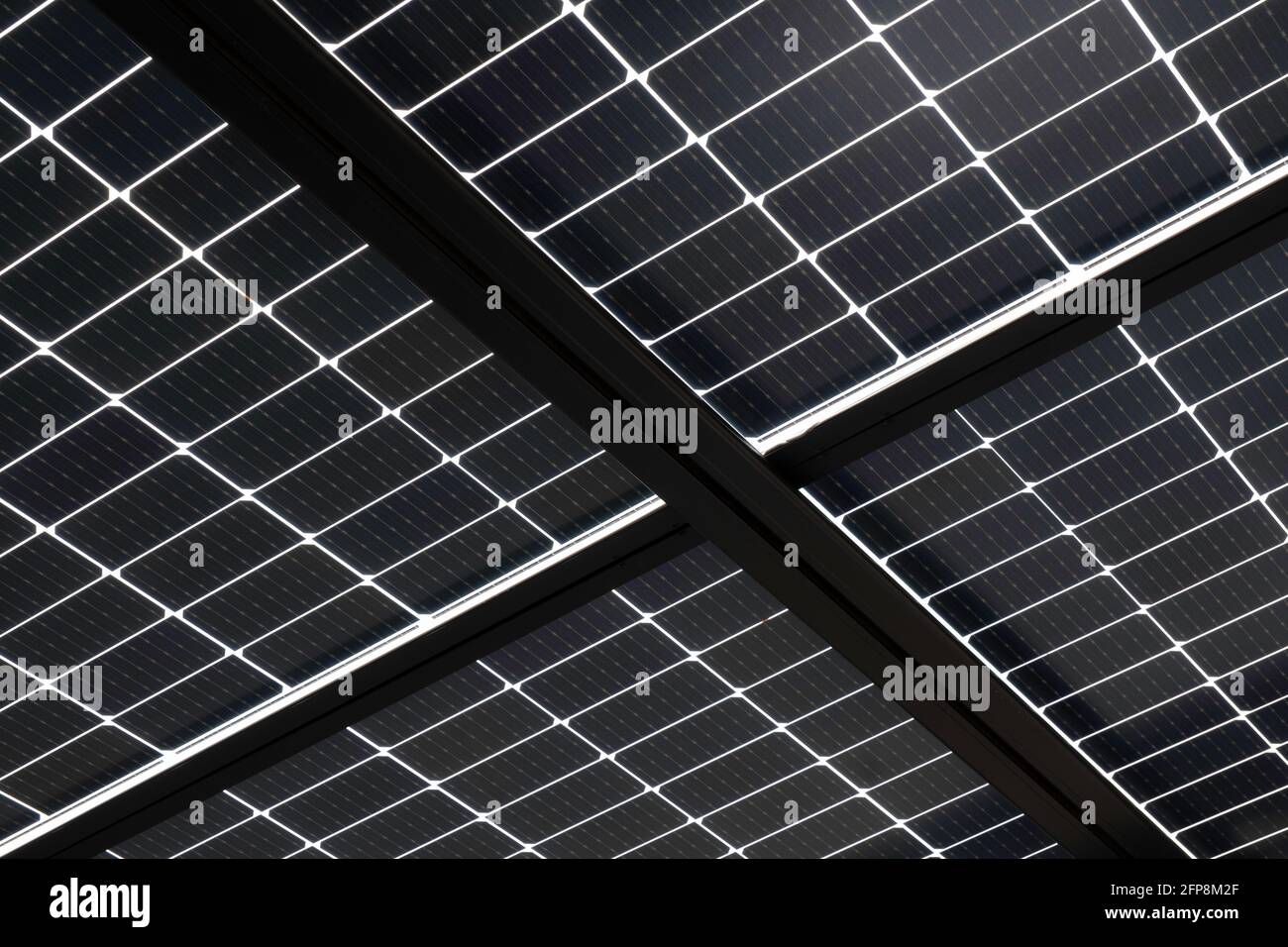 Pannelli solari installati su travi in acciaio per coprire un parcheggio, visto dal basso. Energia sostenibile e ombra allo stesso tempo Foto Stock