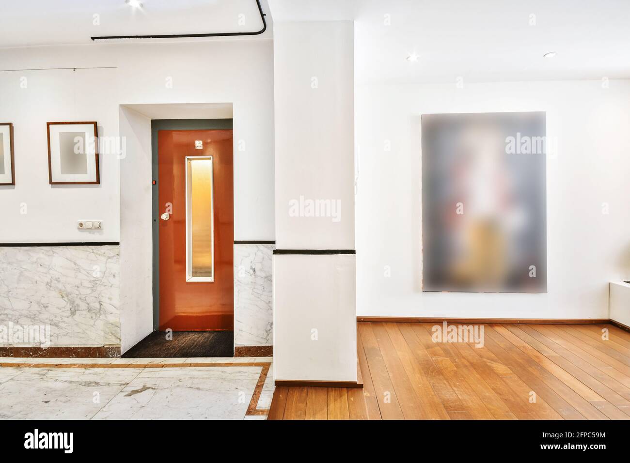 Particolare interno dell'appartamento open space con porta d'ingresso e dipinti d'arte appesi su pareti bianche Foto Stock