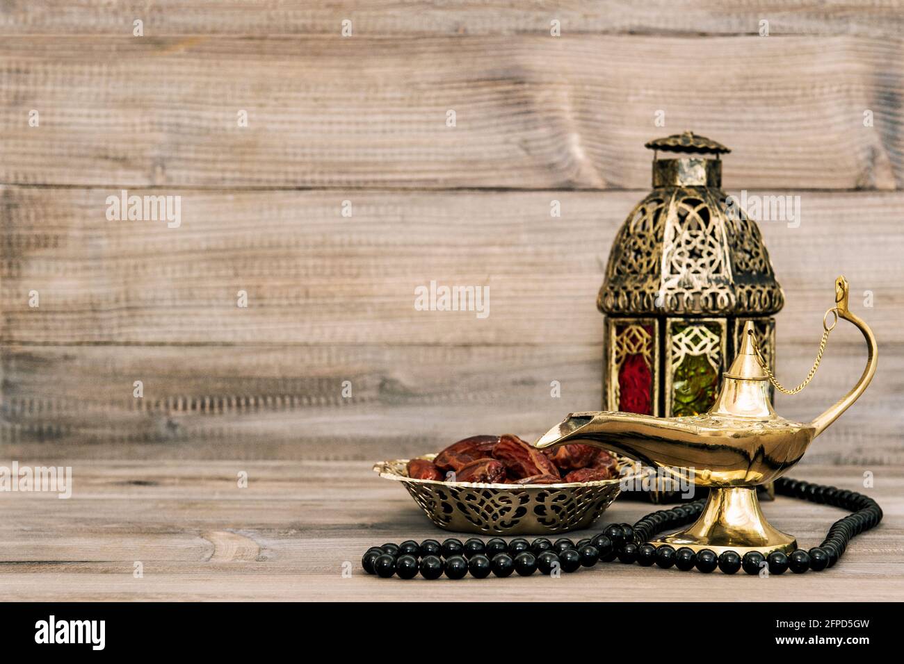 Lampada orientale e datteri su sfondo di legno. Arabo ancora vita con rosario Foto Stock