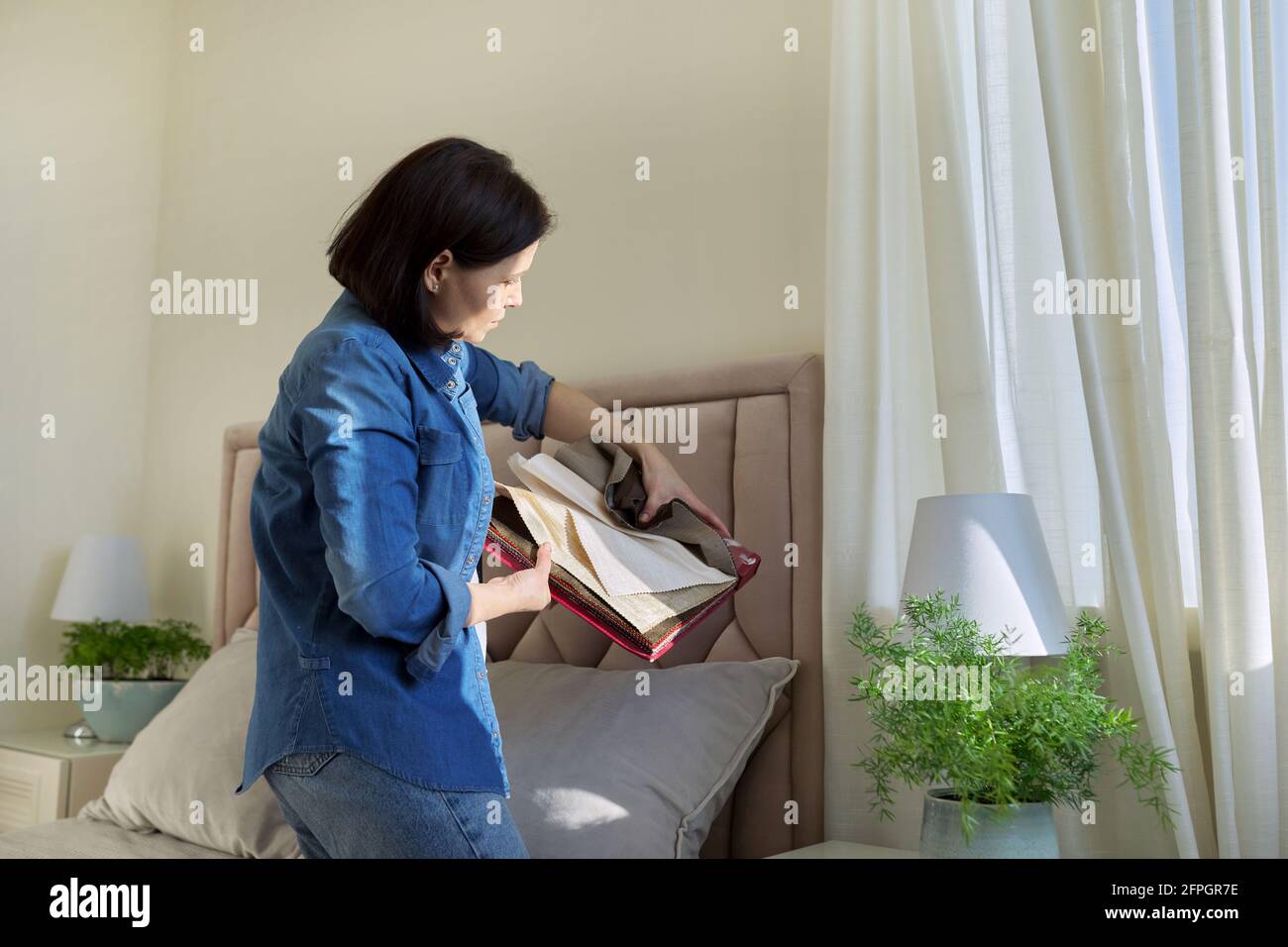 Donna con campioni di tessuti per interni scegliendo tessuti per tappezzeria, tende Foto Stock