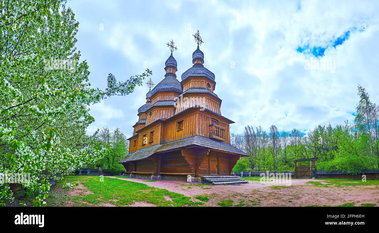 Panorama della chiesa in legno di intercessione della Vergine Maria con alberi da frutto fioriti intorno ad essa, Mamajeva Sloboda Cossack Village, Kiev, Ucraina Foto Stock