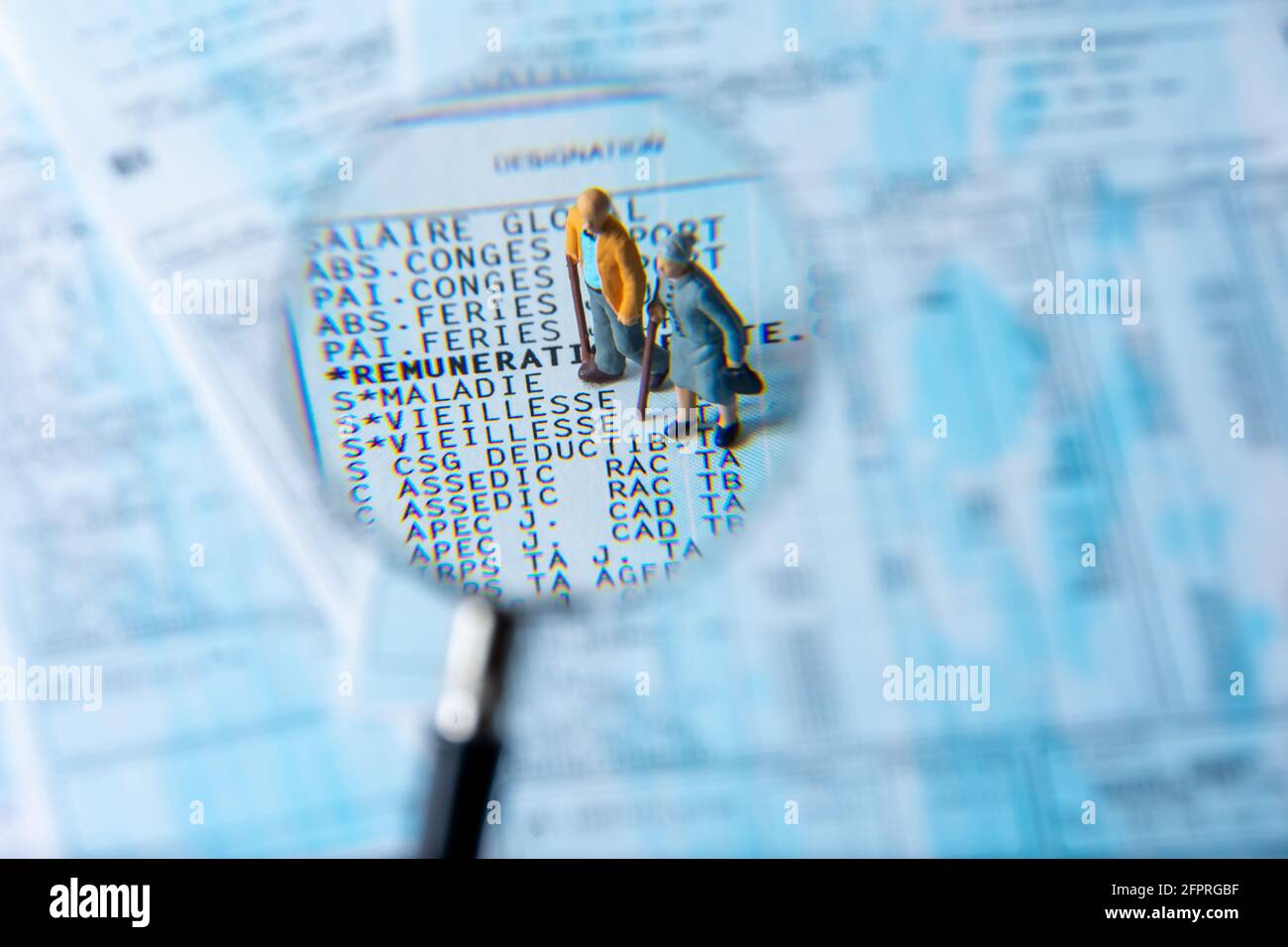 Libro paga francese visto in dettaglio attraverso una lente di ingrandimento che mostra i contributi di previdenza sociale per la pensione e la malattia, con piccole figurine Foto Stock