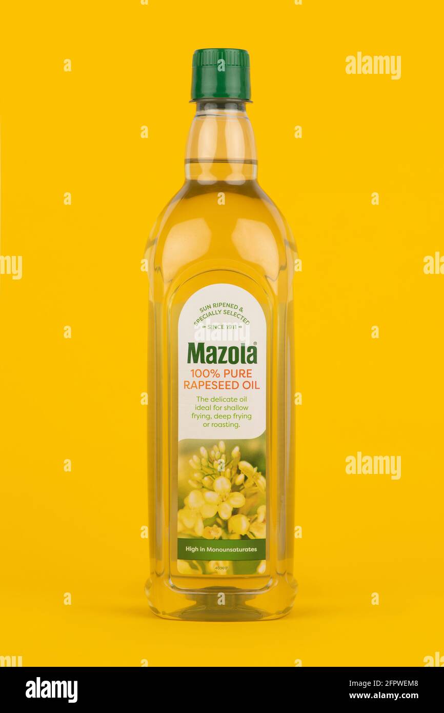Una bottiglia di Mazola 100 e olio di colza puro sparato su uno sfondo giallo. Foto Stock
